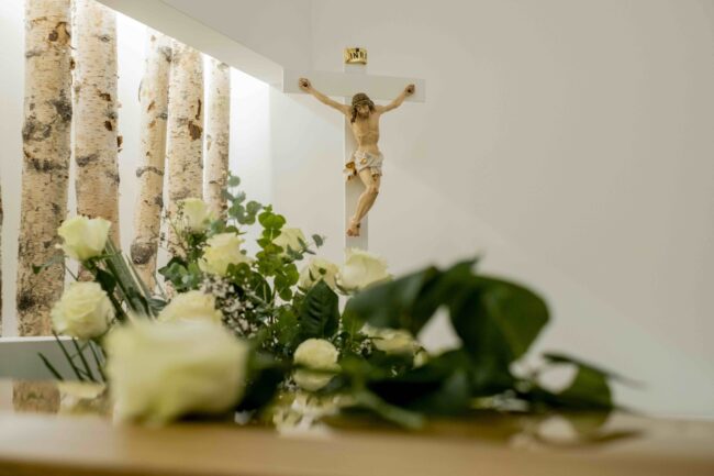 Quanto costa un funerale in chiesa Primo piano di rose bianche su una bara e crocifisso sullo sfondo